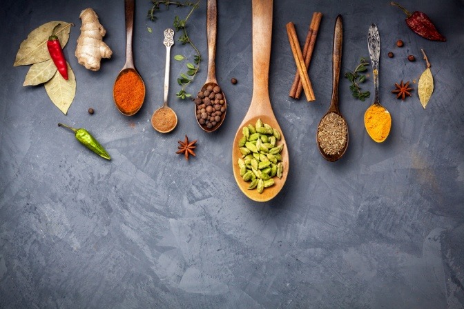 Es hängen viele Kochlöffel mit Gewürzen nach Ayurveda