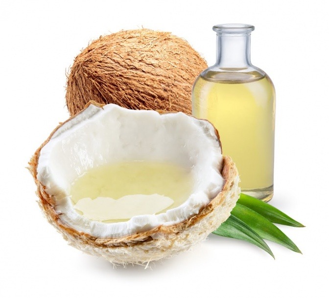 Eine Kokosnuss liegt neben einem Fläschchen Öl