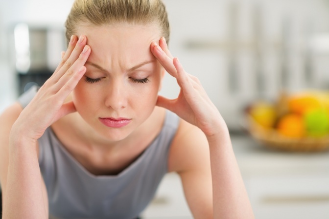 Eine Frau hält ihren Kopf wegen Kopfschmerzen