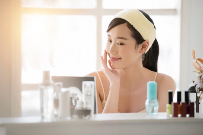 Frau vor dem Spiegel mit koreanischer Kosmetik