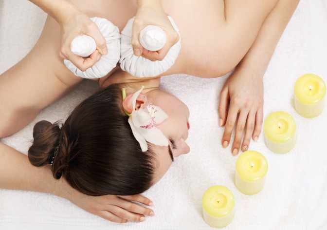 Eine Frau bekommt eine Kräuterstempelmassage