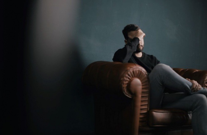 Ein Mann in seiner Lebensmitte sitzt mit einer Krise auf einem Sofa