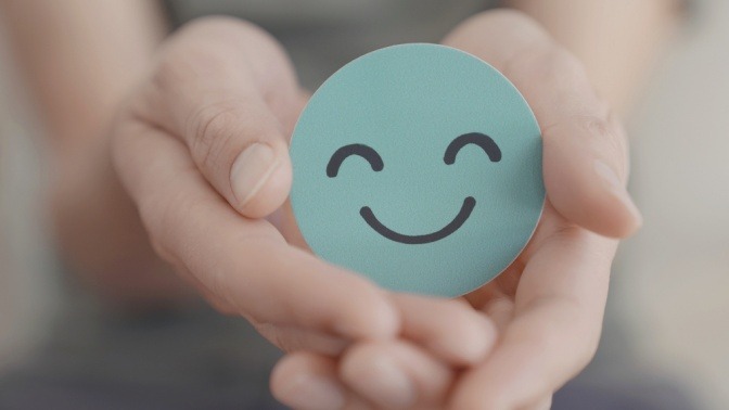 Zwei Hände halten einen lächelnden Smiley