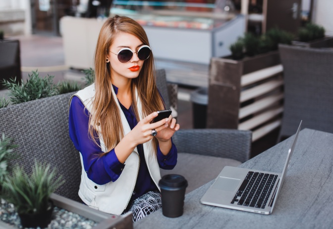 Eine Frau mit Laptop und Handy in einem Café