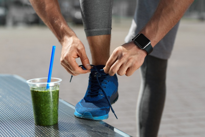 Mann bindest Schuhbänder neben Smoothie