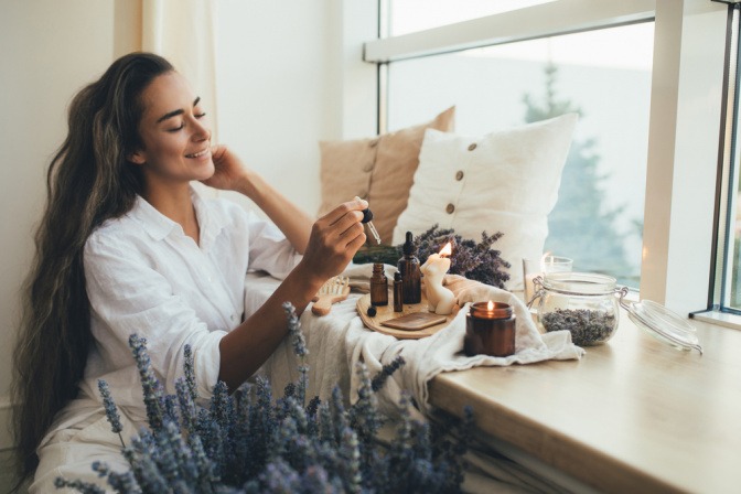 Frau mit Lavendel und Lavendelöl am Fenster.