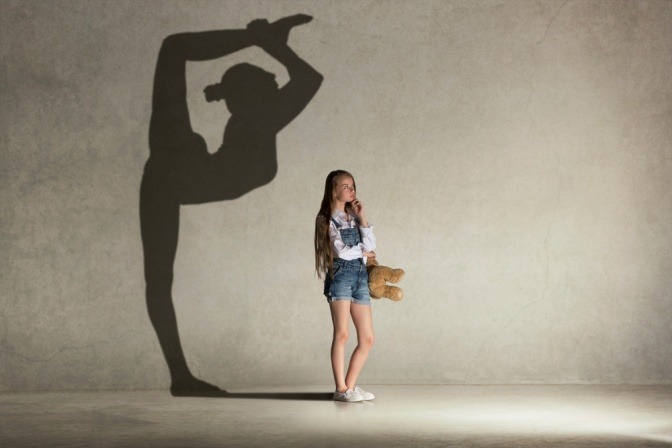 Eine junge Frau steht vor einem Hintergrund, auf dem eine andere tanzt