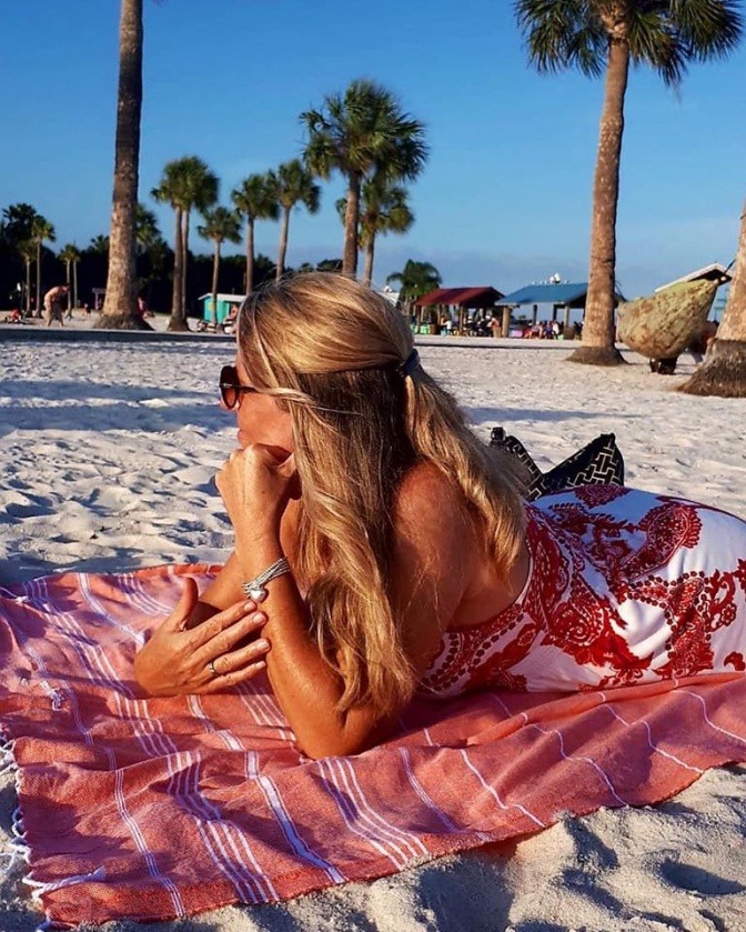 Frau liegt auf einem modischen Tuch am Strand