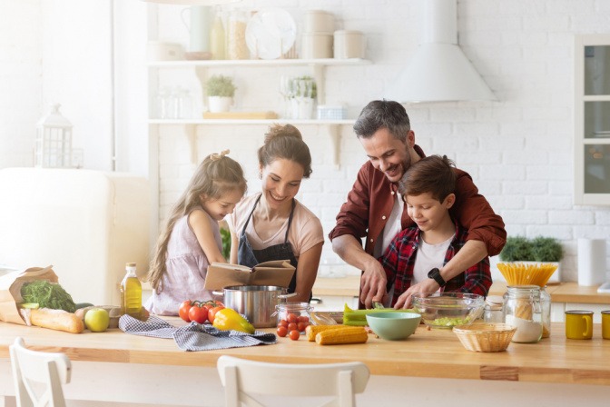 Familie sitzt zusammen beim Kochen in der Küche. 