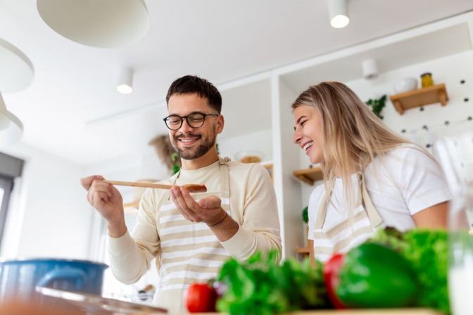 Junges Paar beim Kochen in einer optimal beleuchteten Küche.
