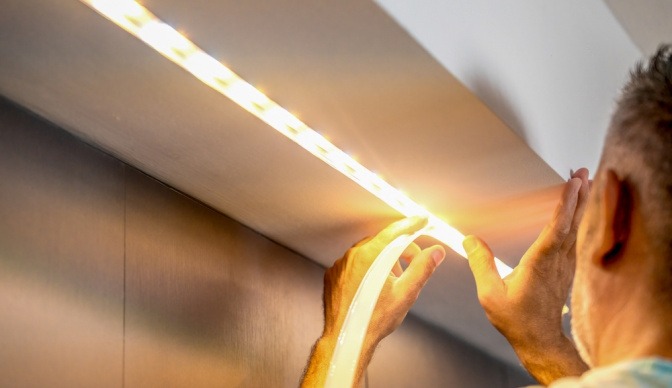Mann bringt LED-Lichtleiste in einer Küche an.