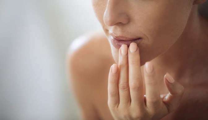 Eine Frau pflegt ihre Lippen mit Sheabutter