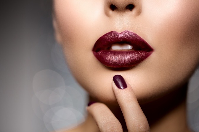 Eine Frau hat Lippenstift in einem dunklen Beerenton