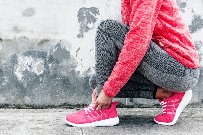 Eine Frau hat einen Trainingsanzug in der Trendfarbe Living Coral an