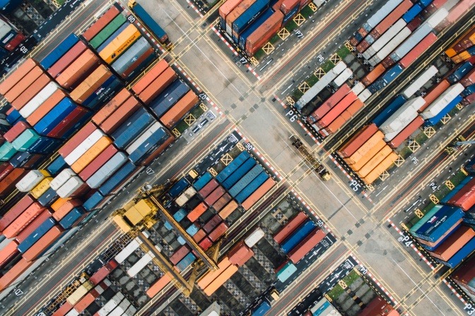 Ein Foto aus der Vogelperspektive zeigt einen Containerpark an einem Hafen.