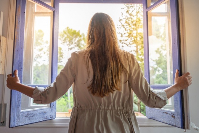 Frau vor offenem Fenster