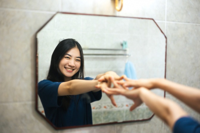 Frau lächelt sich selbst im Spiegel an