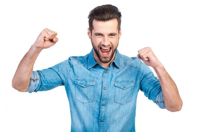 Ein Mann reckt die Arme triumphierend in die Höhe, es wirkt als habe er gerade eine Aufgabe abgeschlossen, worüber er sich nun sehr freut.