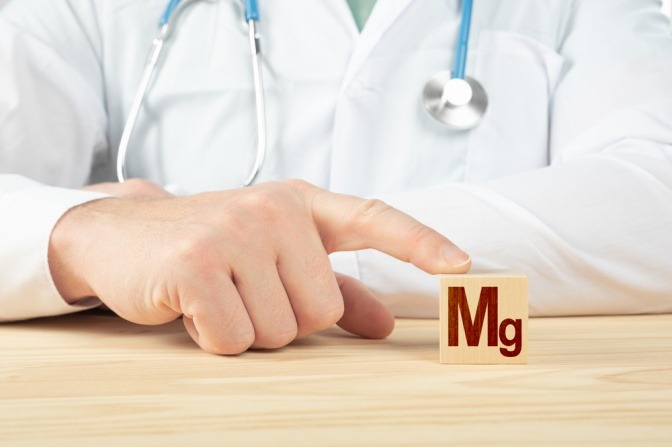 Arzt hält Würfel mit Mg (Magnesium)