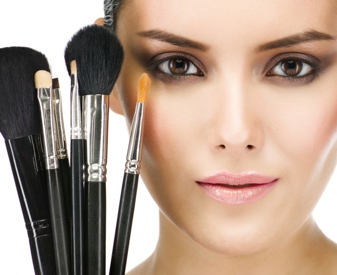 Neben einem Gesicht sind verschiedene Make-up Pinsel
