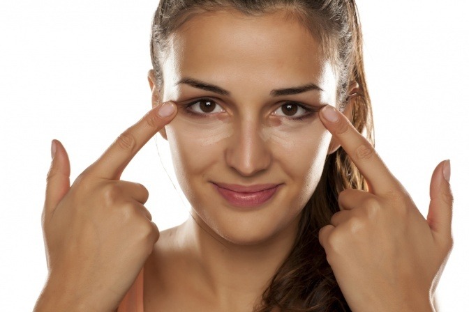 Eine Frau trägt Make-up gegen Augenringe auf