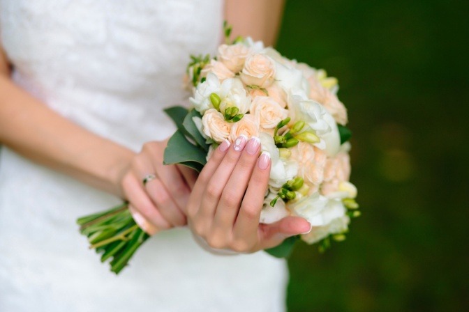 Frau mit Blumenstrauß für die Hochzeit mit manikürten Nägeln