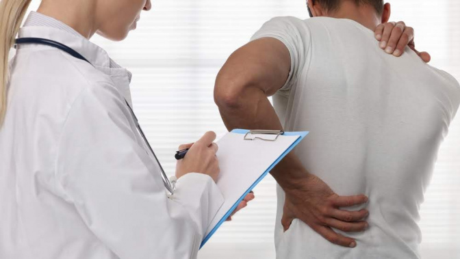 Ein Mann lässt seine Rückenprobleme von einer Ärztin untersuchen