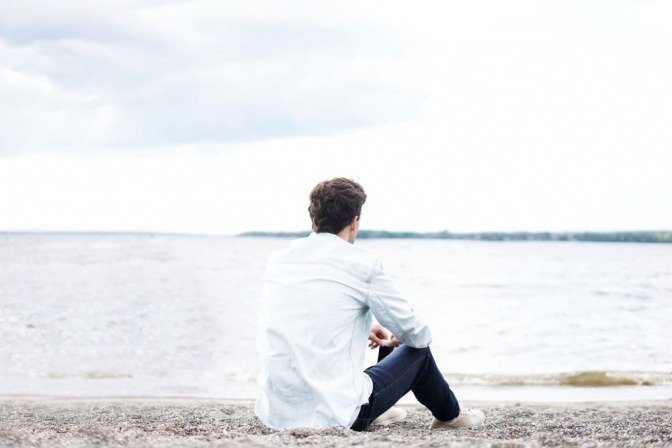Ein Mann sitzt einsam am Strand