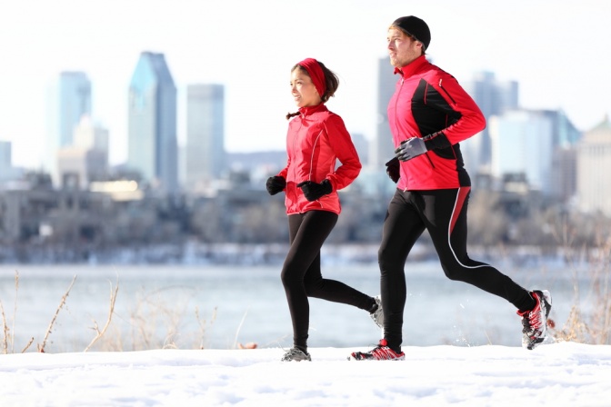 Ein Mann und eine Frau joggen vor einer winterlichen Stadt