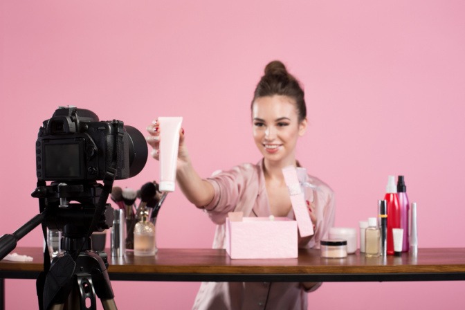 Frau hält Kosmetikprodukt vor eine Kamera