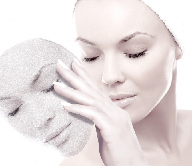 Eine Frau hält eine Maske mit der Form ihres Gesichts vor ihr
