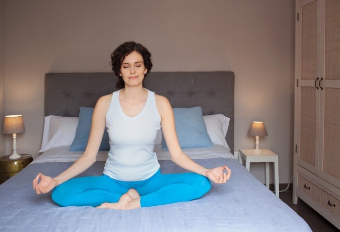 Eine Frau meditiert entspannt im Bett