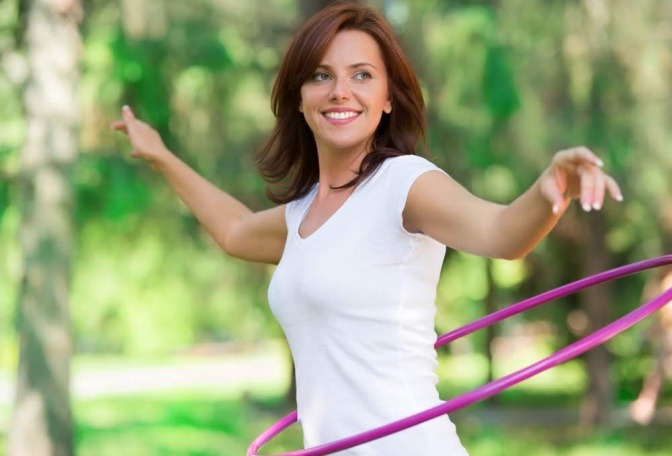 Eine Frau lässt ein Hula-Hoop Reifen um ihre Hüfte schwingen