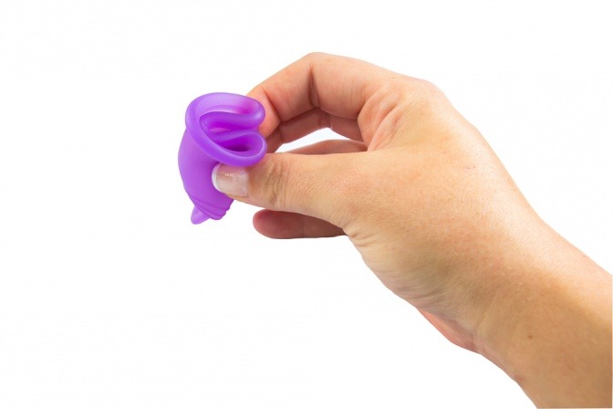 Eine Hand klappt eine Menstruationstasse zusammen