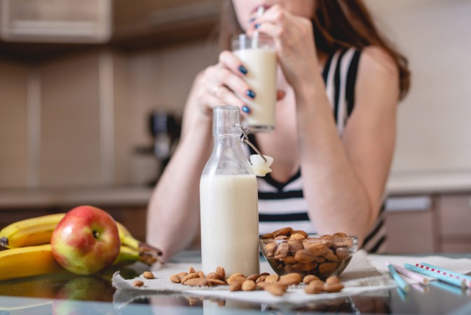 Frau trinkt selbstgemachte Mandelmilch.