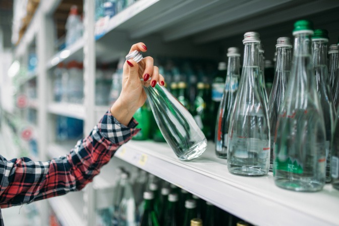 Frau kauft Mineralwasserflasche im Supermarkt.