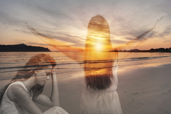 Eine Frau meditiert am Meer bei Sonnenaufgang.