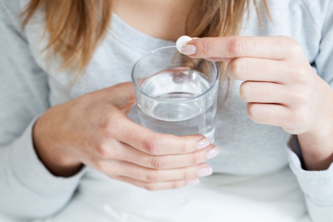 Eine Frau gibt eine Brausetablette als Mittel gegen Erkältung in ein Glas