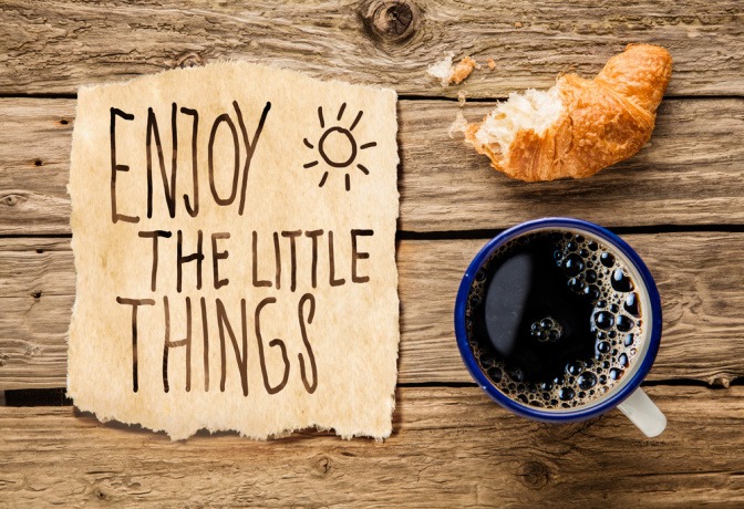 Kaffe, Croissant und ein Zettel mit der Aufschrift "Enjoy the little things"