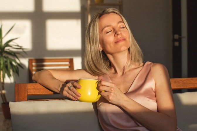 Eine Frau genießt eine Tasse Tee und Sonnenstrahlen