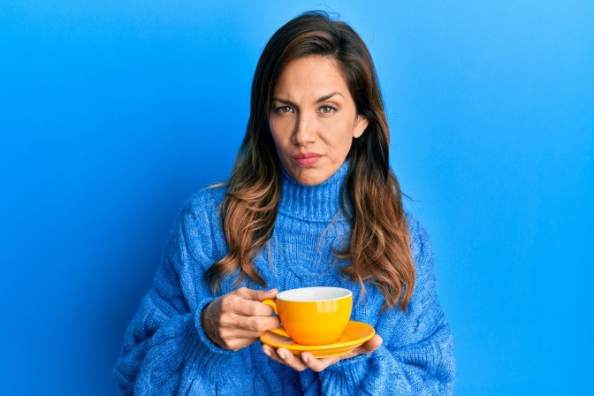 Morgenmuffel was tun? Eine schlecht gelaunte junge Frau mit einer Tasse in der Hand.