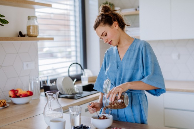 Junge Frau mischt in ihrer Küche ein Müsli an.