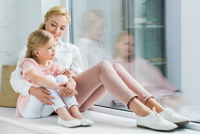 Eine Mutter sitzt entspannt mit dem Kind auf dem Bett