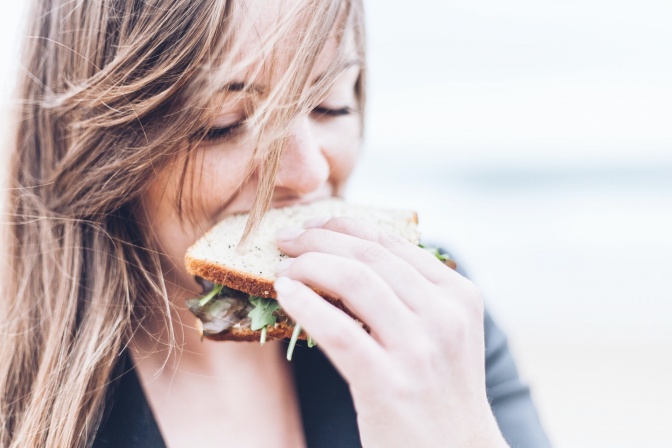 Eine Frau beißt in ein Sandwich mit Salat