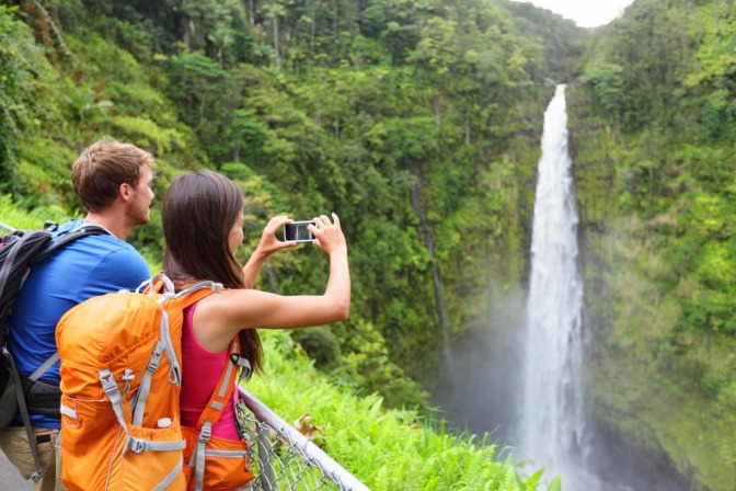 Junges Paar macht Fotos von einem Wasserfall.