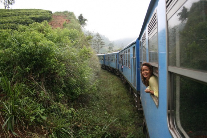 Junge Frau schaut aus einem fahrenden Zug in einer beliebten Urlaubsdestination.