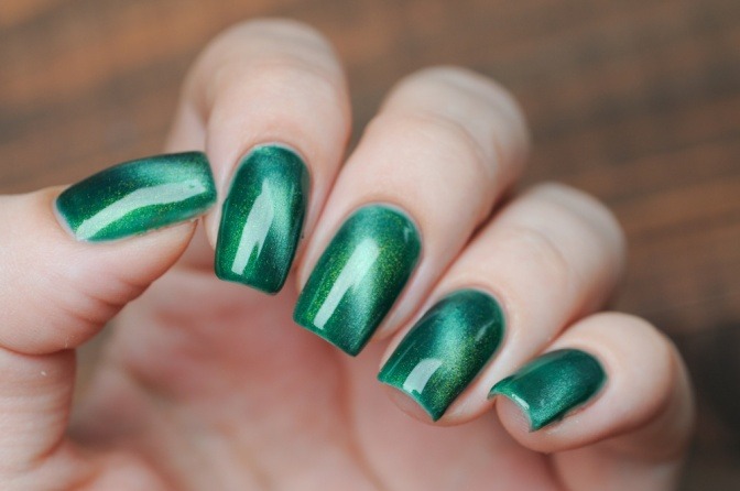 Eine Frauenhand mit grün lackierten Fingernägeln.