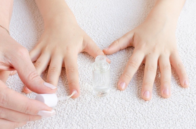 Eine Mutter trägt ihrem Kind bitteren Nagellack auf.