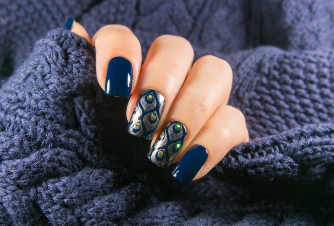 Eine Hand mit blauen Fingernägeln hält etwas Gestricktes