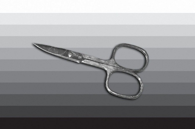 Eine silberne Nagelschere liegt vor einem grau-weiß-gestreiften Hintergrund